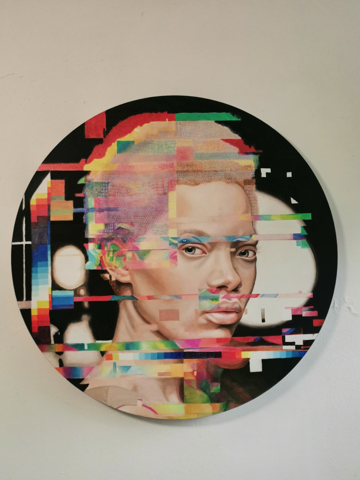 Circular portrait artwork with digital glitch effect overlaying a persons face with colorful pixelated blocks